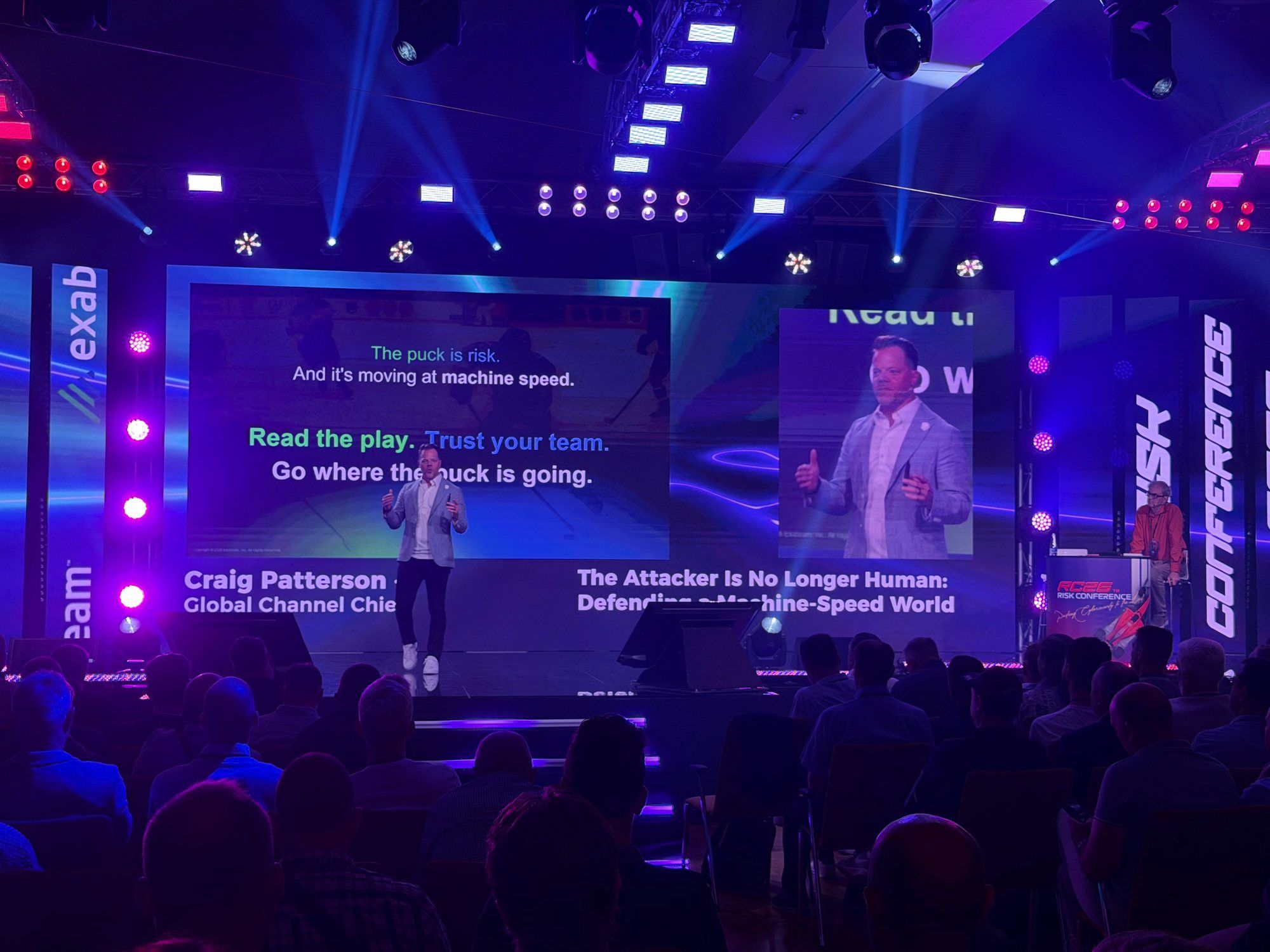 Craig Patterson on stage in front of a slide reading "Read the play. Trust your team. Go where the puck is going."